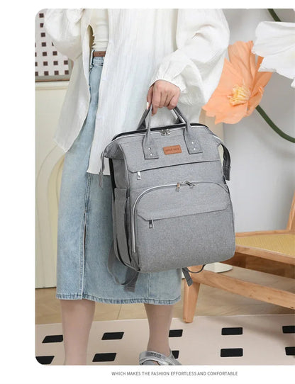 Sac a langer gris porte a la main, elegant et polyvalent pour les rendez-vous en ville.