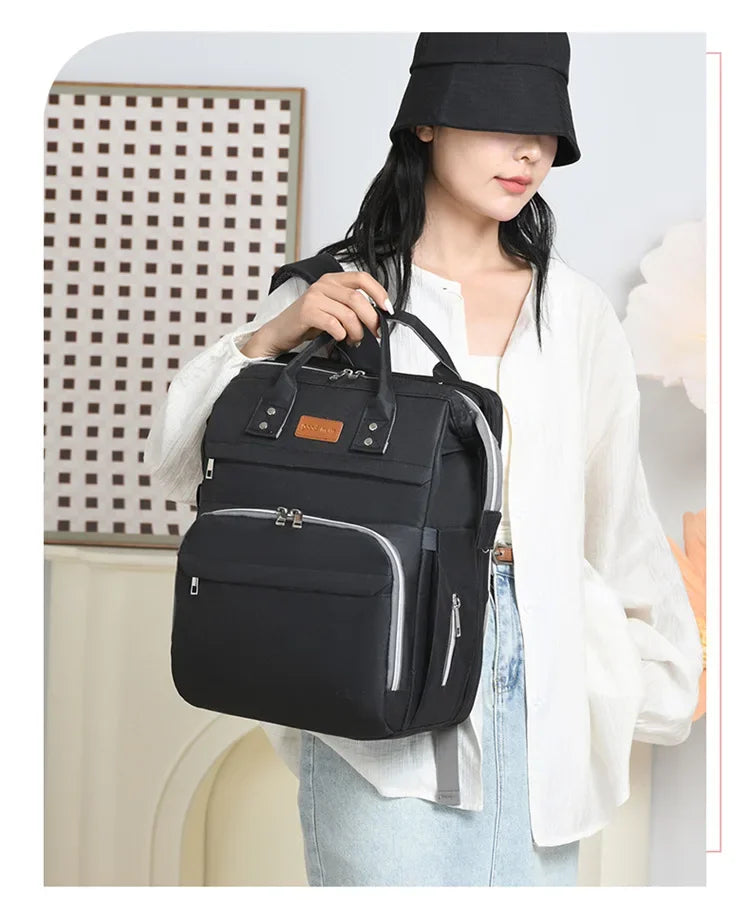 Sac a langer noir tenu a la main, un accessoire discret qui s'accorde a toutes les tenues.