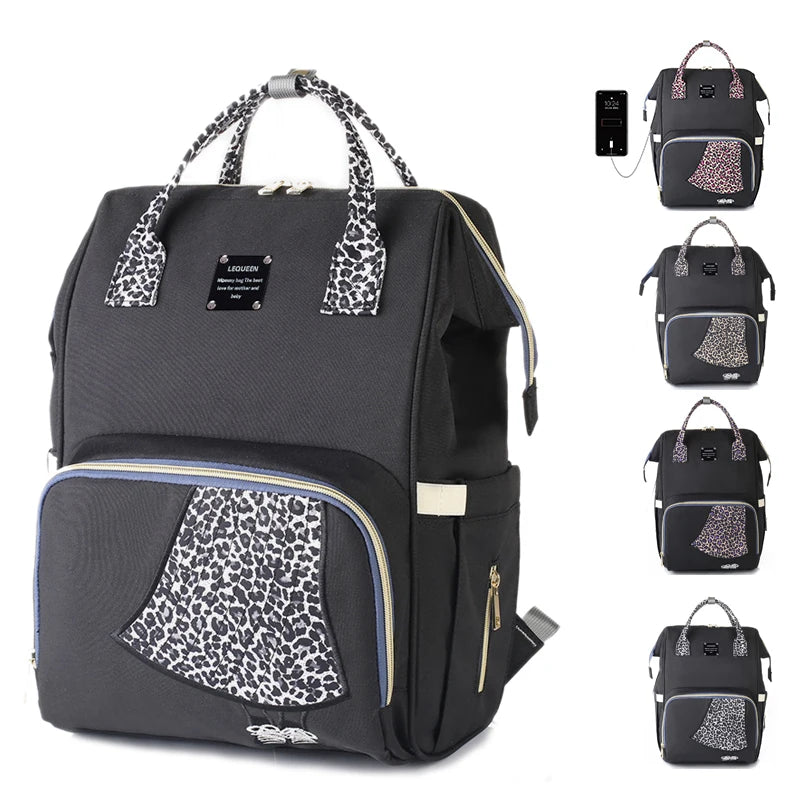 Sac a langer leopard noir decline en plusieurs coloris de motifs, avec port USB integre pour recharger son telephone en deplacement.