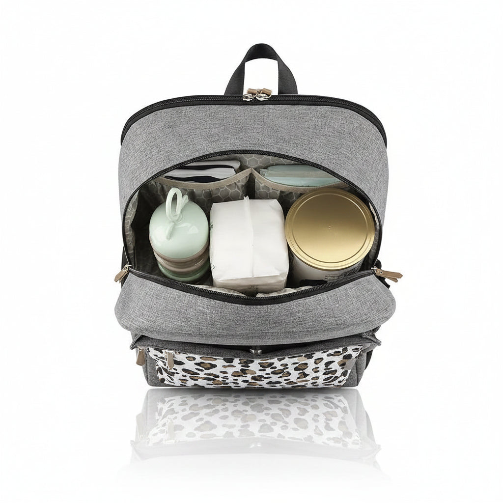 Interieur du sac a langer leopard ouvert montrant ses compartiments separes pour ranger biberons, lait et couches de maniere ordonnee.