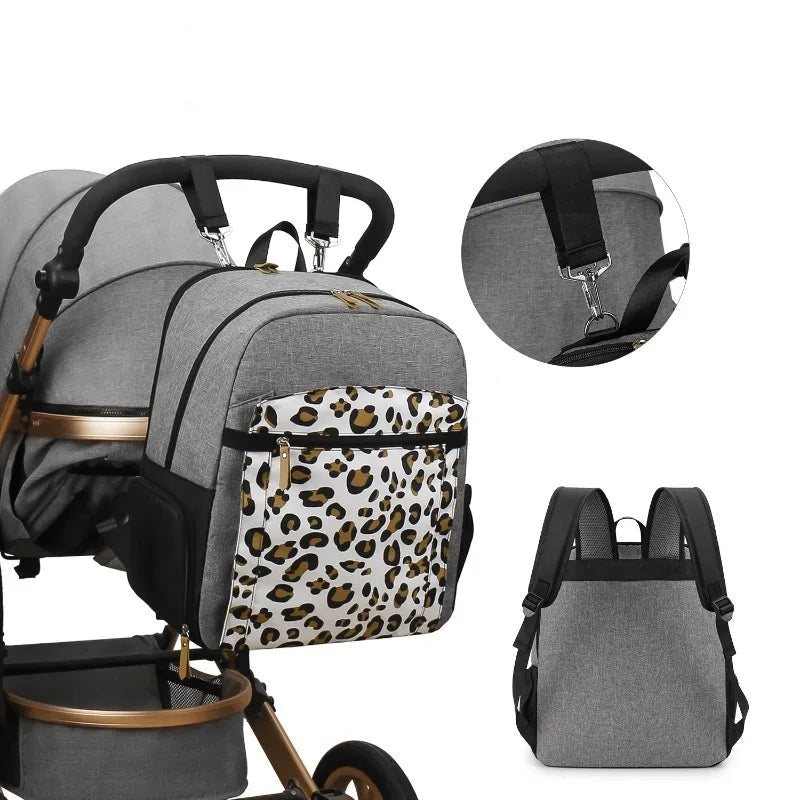 Sac a langer leopard accroche a une poussette grace a ses sangles amovibles, liberant les mains des parents pendant la promenade.