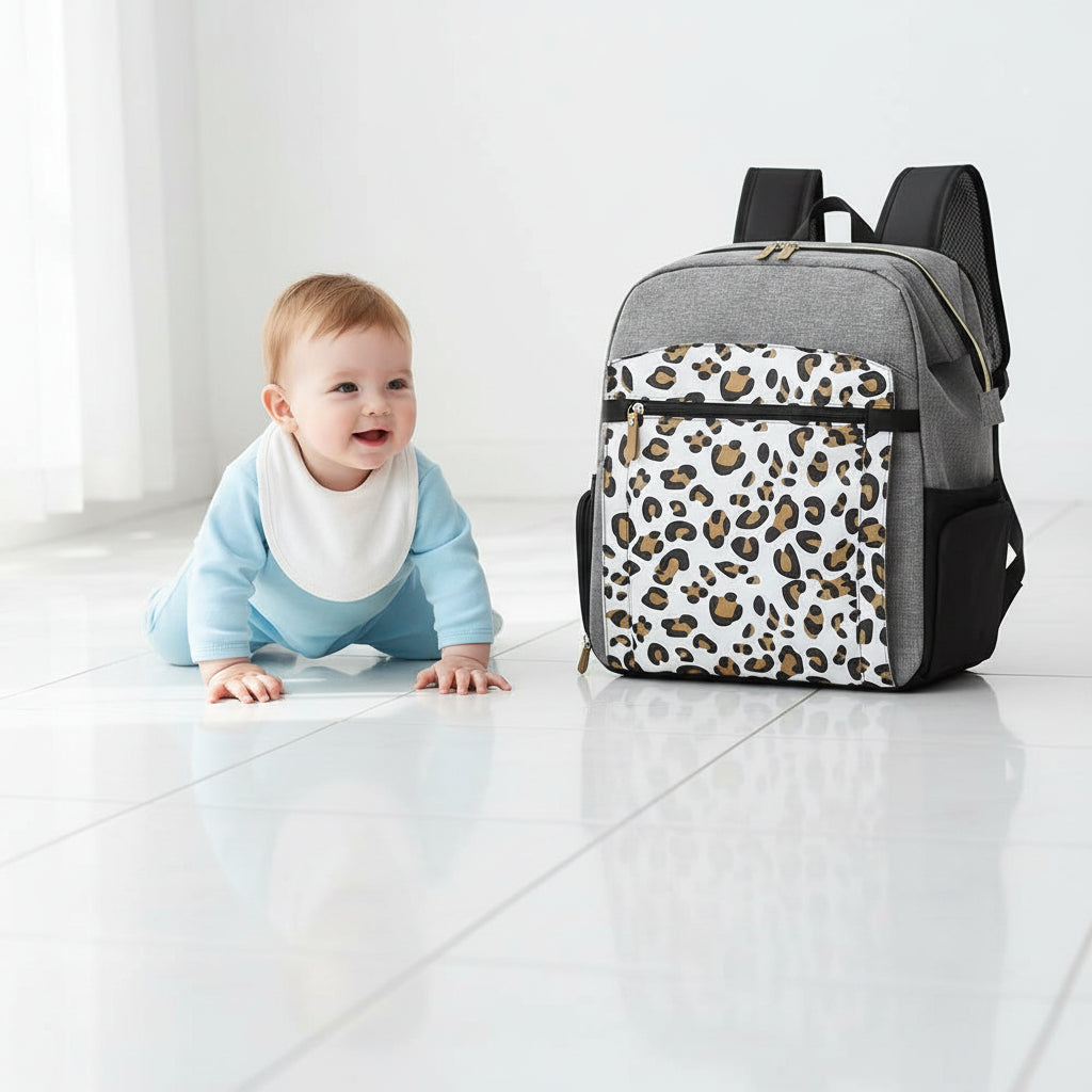 Sac a langer leopard presente a cote d'un bebe qui rampe, illustrant sa taille pratique pour accompagner les jeunes parents en sortie.