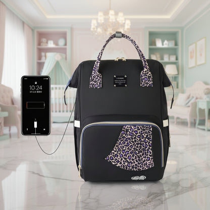 Sac a langer leopard violet equipe d'un cable USB integre permettant de recharger son smartphone sans ouvrir le sac.