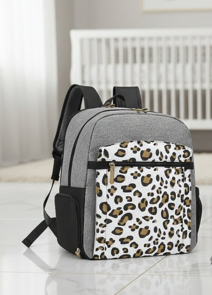 Sac a langer motif leopard gris et blanc pose dans une chambre de bebe, alliant style tendance et praticite au quotidien.