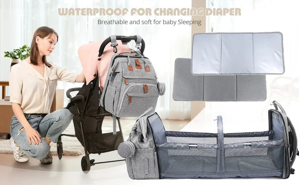 Maman accrochant le sac a langer sur sa poussette lors d'une sortie, avec le matelas a langer impermeable et respirant deploye pour changer bebe partout.