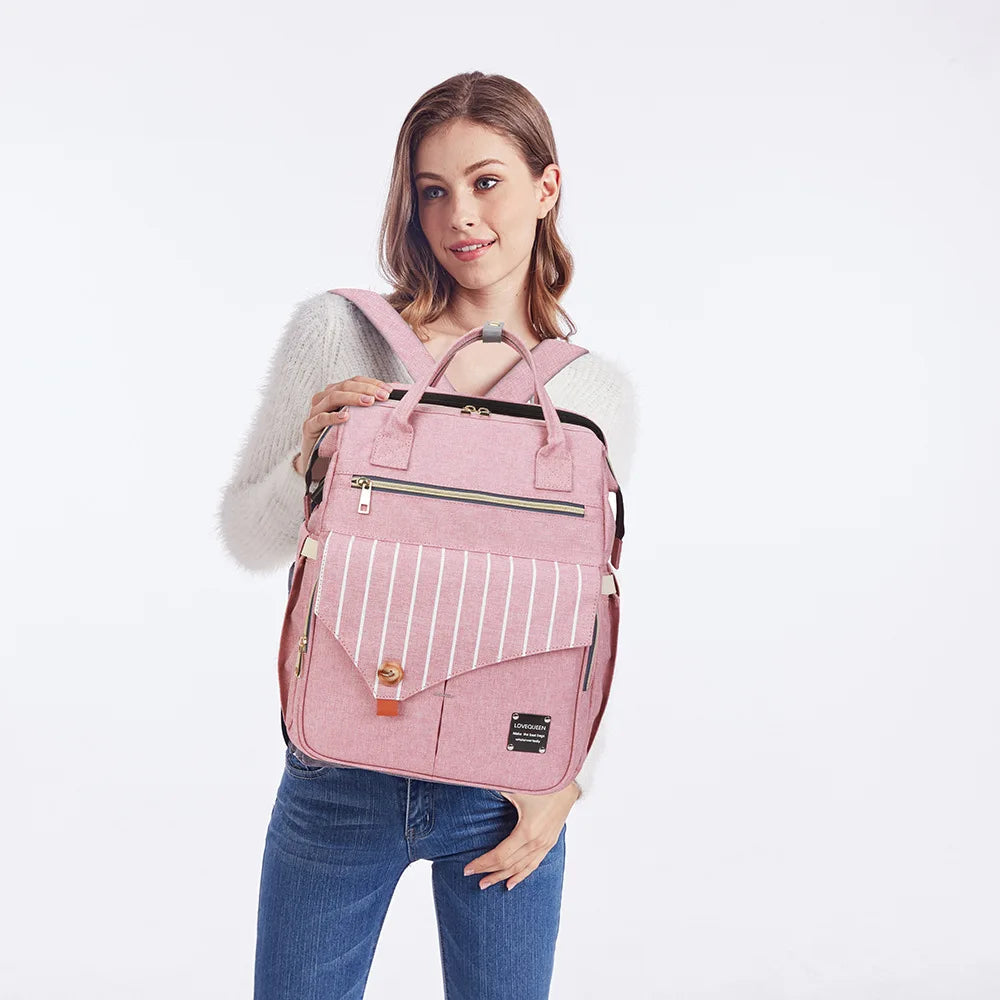Maman ajustant le sac a langer rose sur son dos, offrant les mains libres pour s'occuper de bebe en balade.