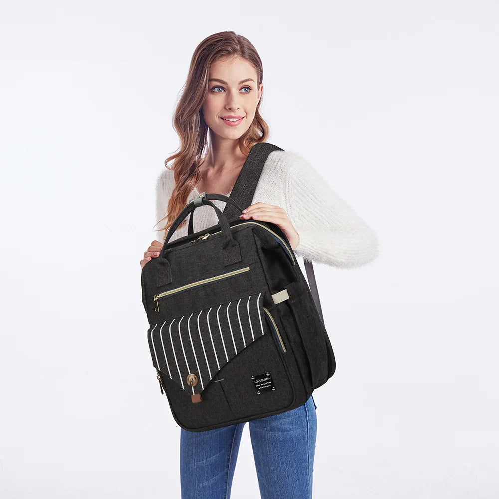 Jeune maman portant le sac a langer noir sur l'epaule, un accessoire elegant qui s'integre a toutes les tenues du quotidien.