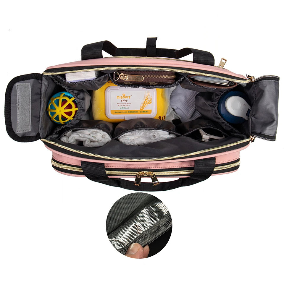 Interieur du sac a langer rose avec ses nombreux compartiments organises et sa poche isotherme pour garder le biberon a temperature.