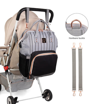 Sac a langer accroche a la poussette grace a ses sangles et mousquetons dores, pour garder les mains libres en balade.
