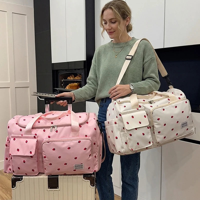 Maman portant le sac a langer en bandouliere avant un depart, la sangle passante sur trolley facilitant les deplacements en famille.