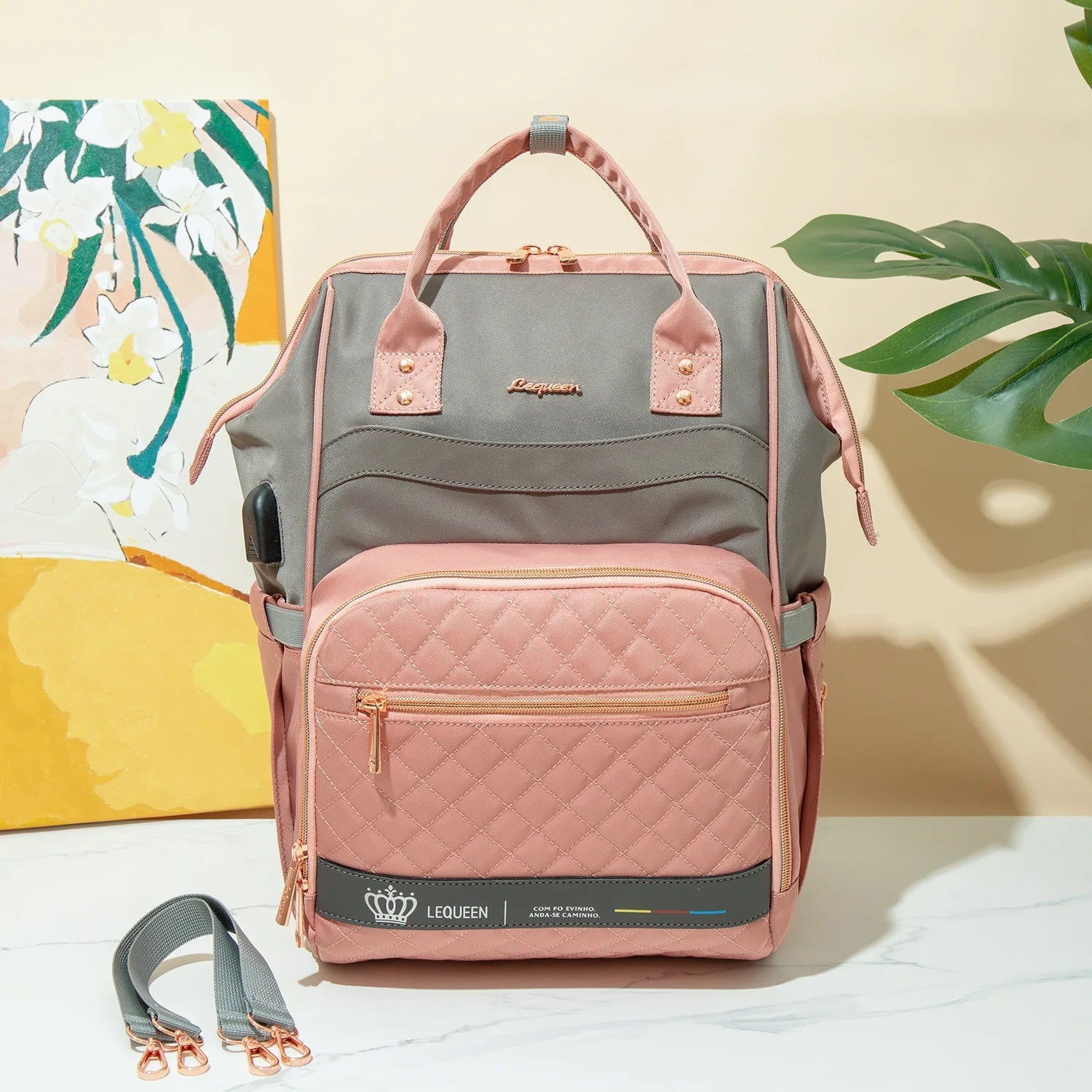 Sac a langer rose et gris au design elegant matelasse, presente en ambiance avec ses sangles de fixation pour poussette.
