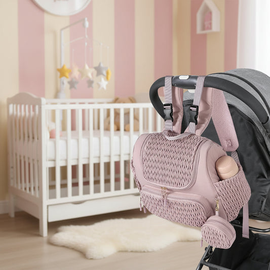 Sac a langer rose fixe sur une poussette grace a ses sangles a clips, pour se deplacer les mains libres en promenade.