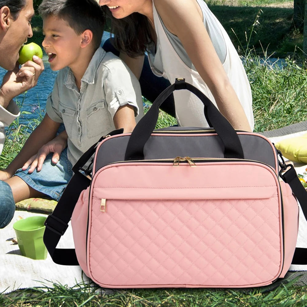 Sac a langer rose emporte lors d'un pique-nique en famille, pratique pour toutes les sorties avec bebe en pleine nature.