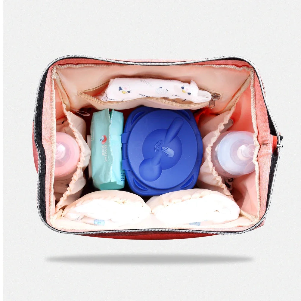 Interieur du sac avec compartiments separes gardant couches, boite a lingettes et biberons parfaitement organises.