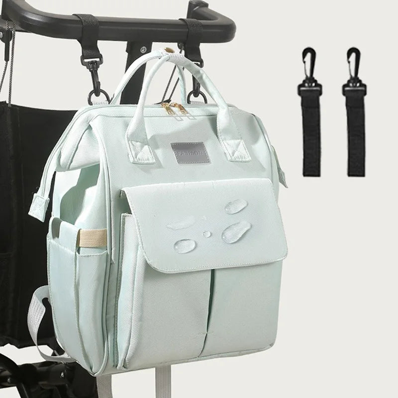 Sac a langer suspendu a une poussette grace aux crochets fournis, pratique pour garder les affaires a portee de main en balade.