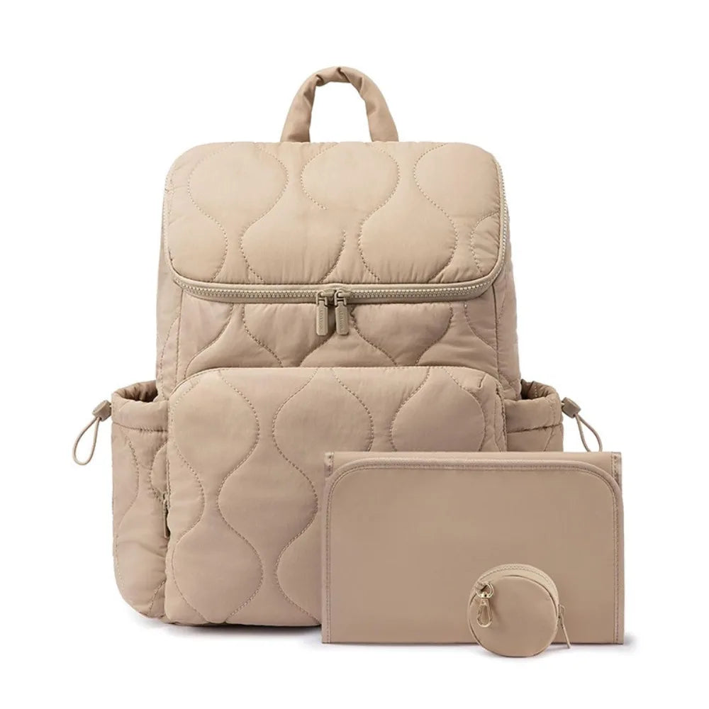 Sac a langer sac a dos matelasse beige livre avec son tapis a langer et sa pochette a tetine assortis pour tout avoir a portee de main.