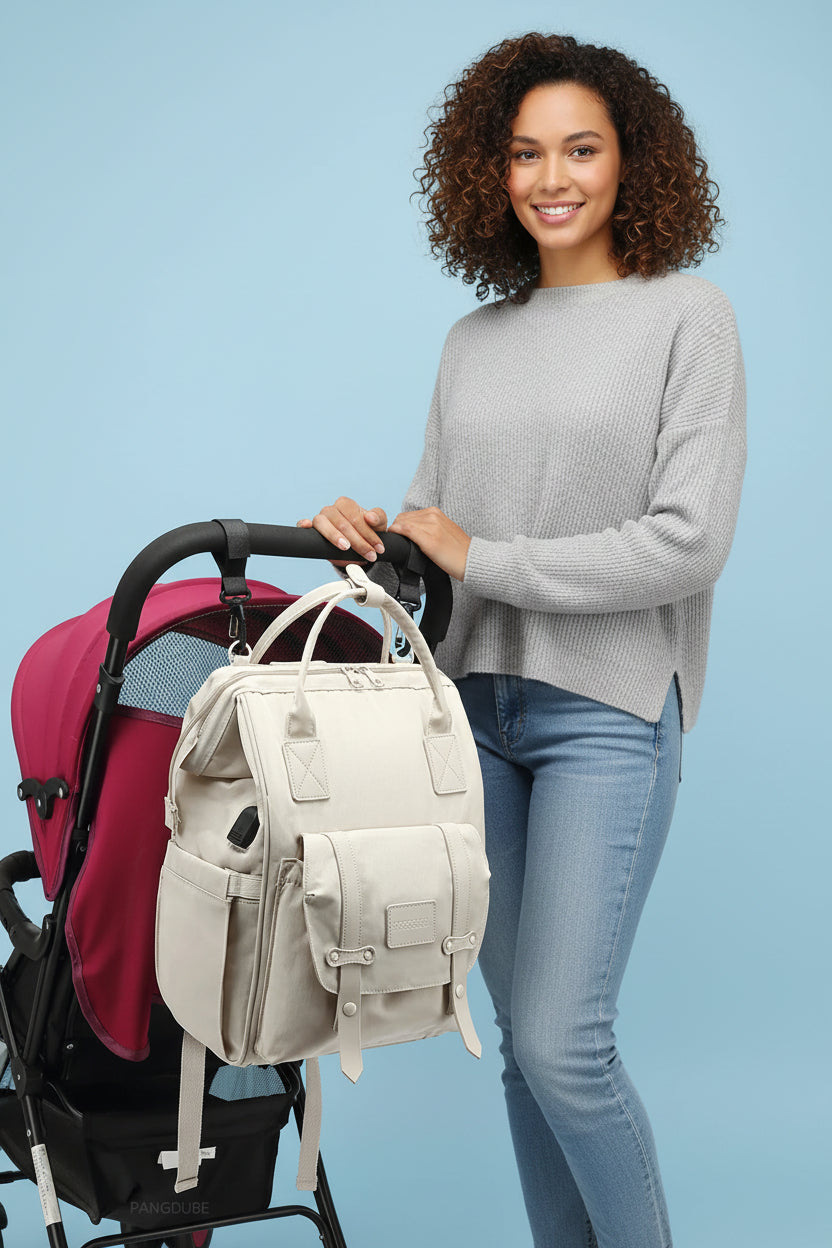 Maman accrochant le sac a langer sac a dos a la poignee de la poussette pour garder les mains libres en balade.