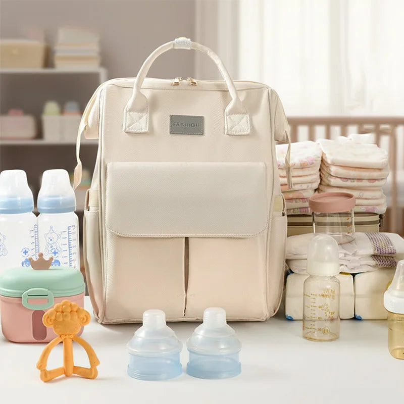 Sac a langer entoure de biberons, couches et accessoires bebe montrant sa grande capacite de rangement pour toute une journee.