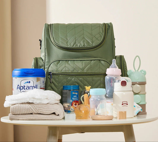 Sac a langer entoure de biberons, lait et accessoires bebe montrant tout ce qu'il peut contenir.