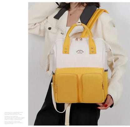 Le sac a langer jaune porte sur l'epaule lors d'une sortie, un format compact qui reste discret et facile a manier.