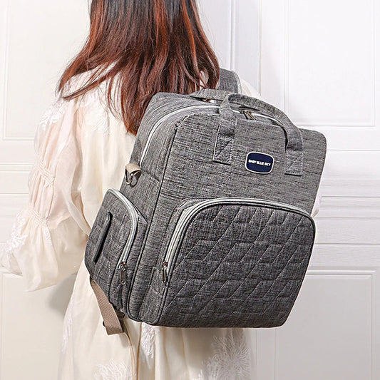 Maman portant le sac a langer sur le dos, libre de ses mains pour s'occuper de bebe en toute serenite.