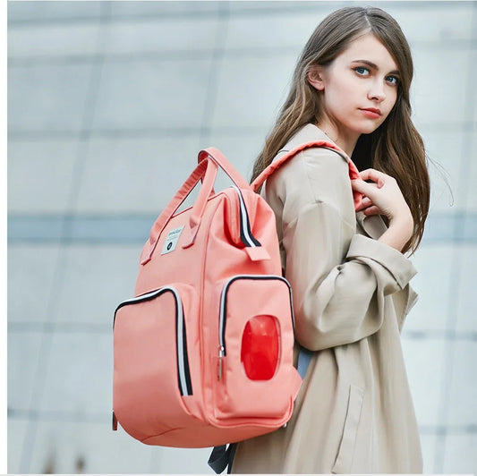 Jeune maman portant le sac a langer sur une epaule, un modele au style urbain qui se fond dans une tenue de ville.