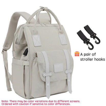 Sac a langer sac a dos beige livre avec une paire de crochets pour fixer facilement le sac a la poussette lors des sorties.
