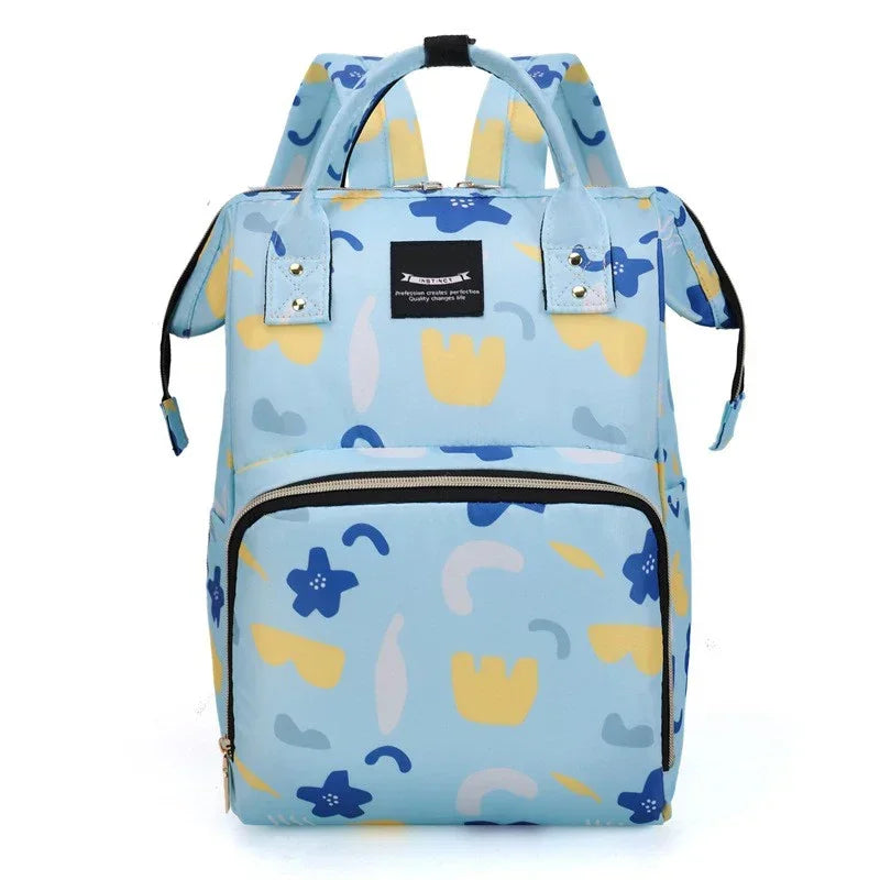 Sac a dos a langer bleu ciel a motif floral avec poignees renforcees, pratique a porter a la main ou sur le dos lors des sorties avec bebe.