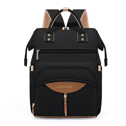 Sac a dos a langer noir aux finitions cognac et dorees, ideal pour transporter les affaires de bebe avec style au quotidien