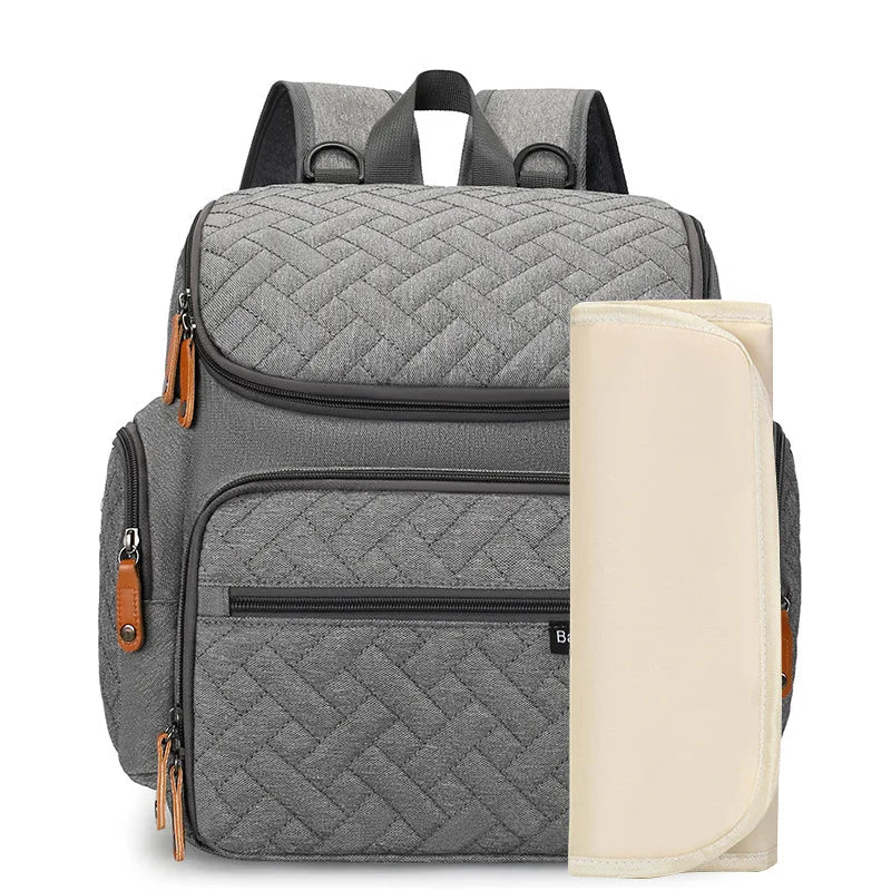 Sac a dos a langer gris livre avec son tapis a langer nomade pour changer bebe partout en toute hygiene.