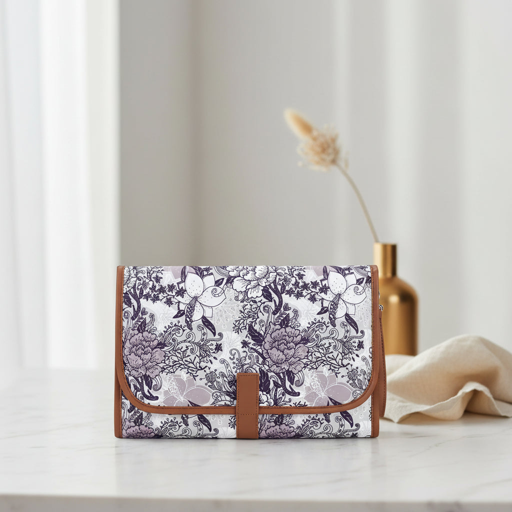 Tapis a langer nomade plie dans un elegant motif floral prune et gris, ideal pour les sorties avec bebe.