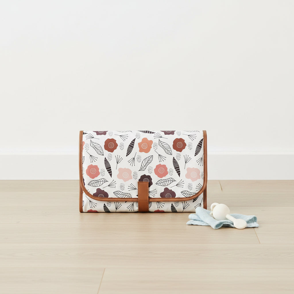 Tapis a langer de voyage impermeable plie dans un imprime floral scandinave sur fond blanc, compact et facile a transporter.
