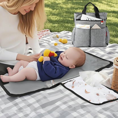 Maman changeant son bebe sur le tapis nomade lors d un pique-nique au parc, prouvant sa praticite en toutes circonstances.