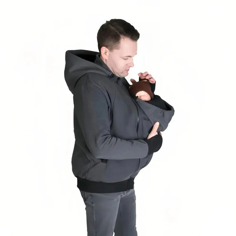 Bebe blotti contre son papa dans la poche de portage de la veste grise, protege du froid tout en gardant les mains libres.