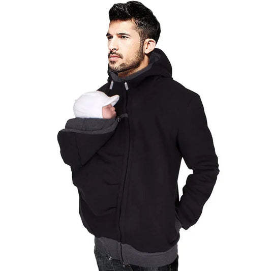 Papa portant son nouveau-ne installe confortablement contre lui grace au panneau de portage integre a la veste.